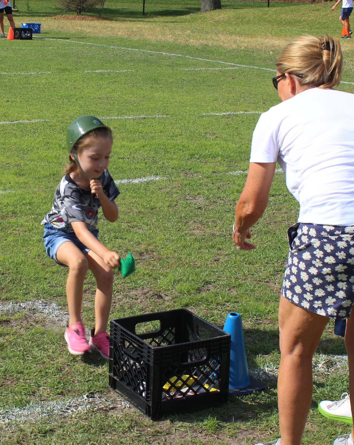 A Bolles student drops a bean bag into a receptacle during a military-themed relay race.